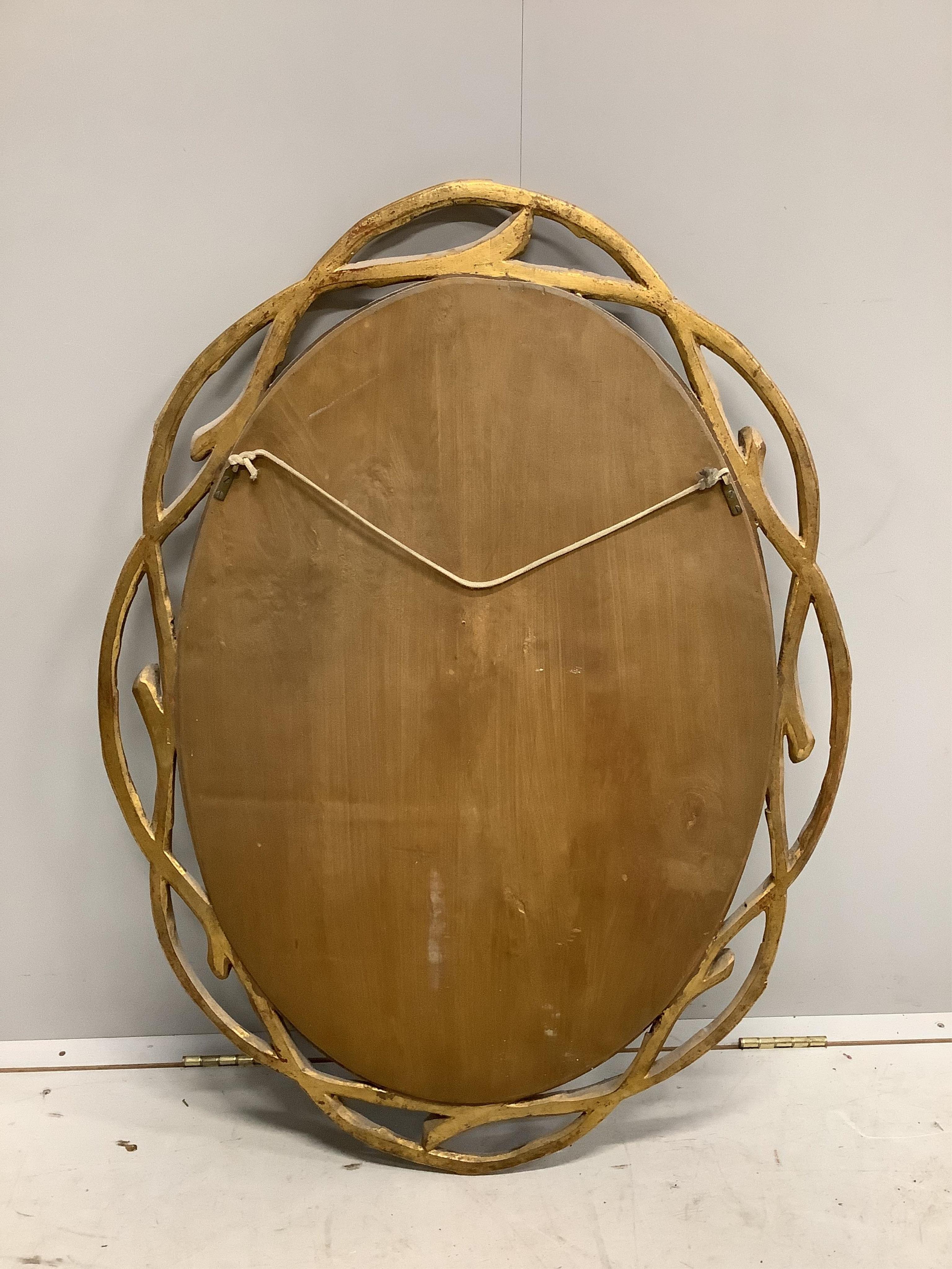 A Contemporary gilt composition oval wall mirror, with branch effect border, width 74cm, height 100cm. Condition - good